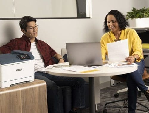 Dos personas en la oficina junto a la impresora en color Xerox® C410