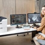 Impresora Xerox® VersaLink® C620 en la oficina Mujer en una oficina junto a la impresora Xerox® VersaLink® C620